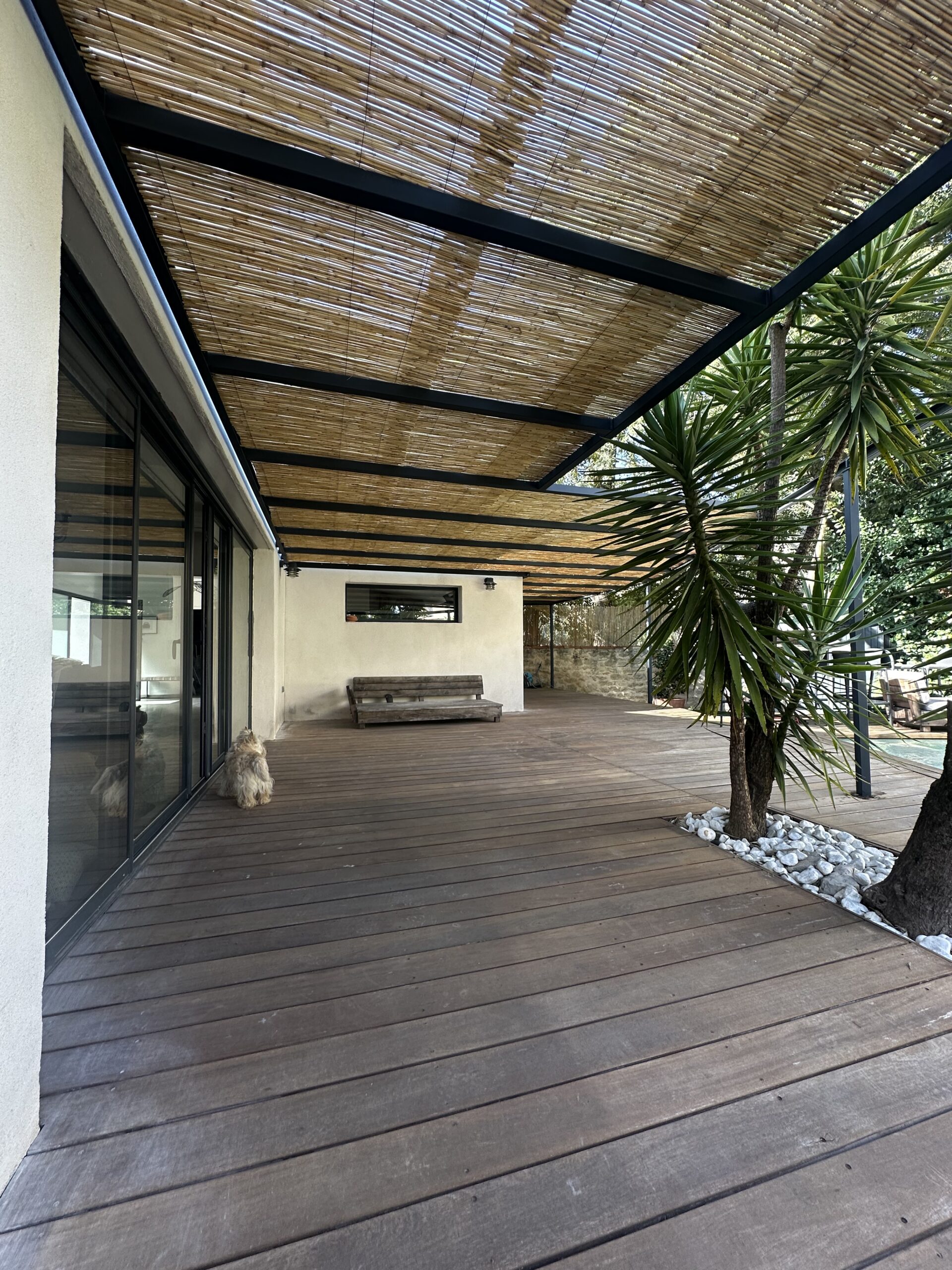 Pergola en acier thermolaqué gris anthracite RAL 7016 couverte de canisses au-dessus d'une terrasse bois à Montpellier
