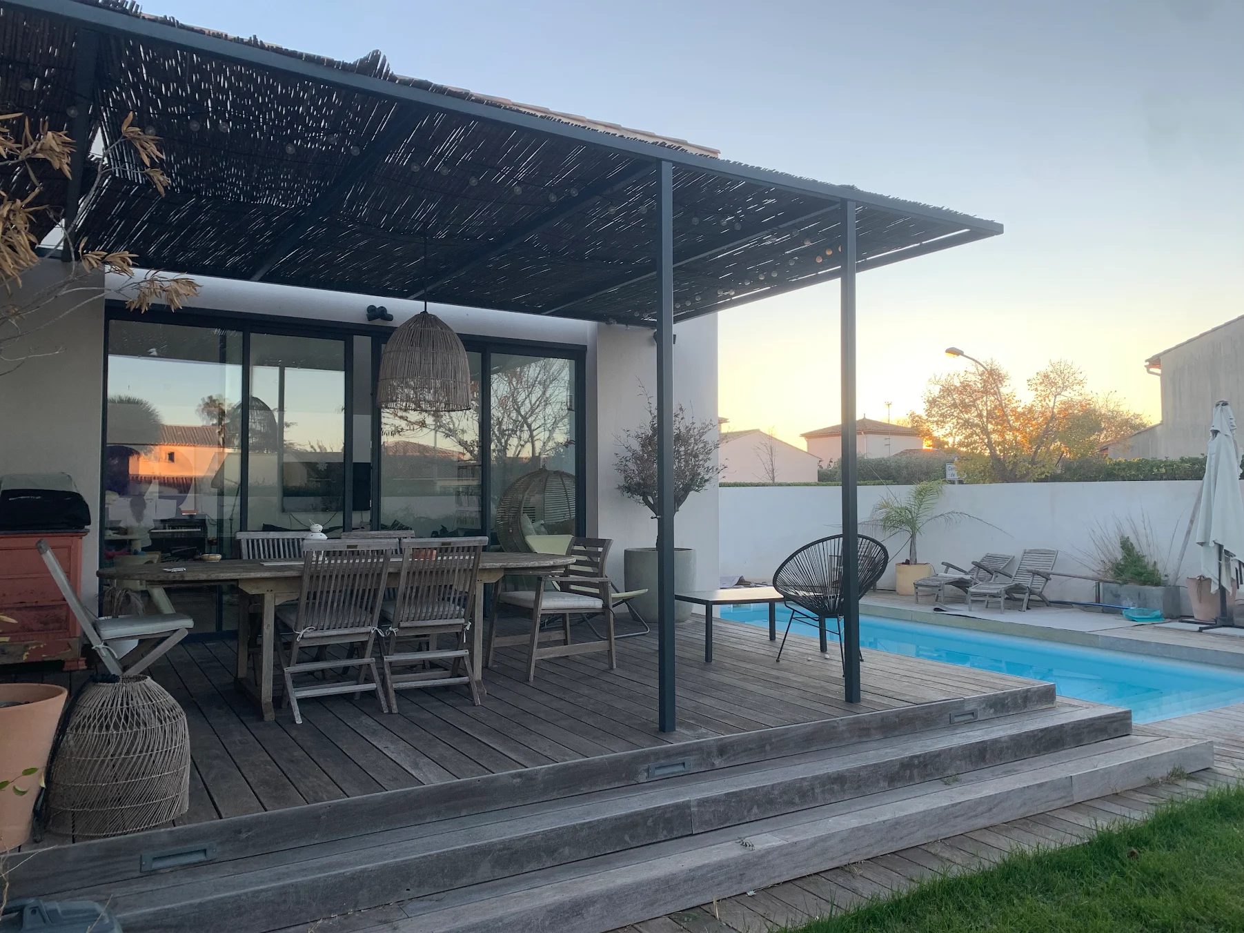 Pergola en acier gris anthracite couverte de canisses au-dessus d'une terrasse bois en bord de piscine à Mauguio, Métallerie Froment